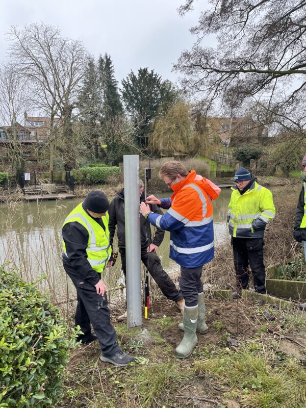 Engineers installing flood-adaptive equipment beside a river