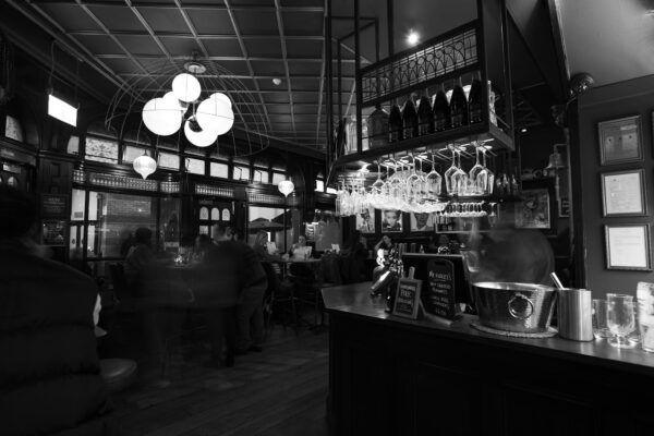 A dimly lit bar with people seated at tables (photo by Eli Nir on Unsplash)
