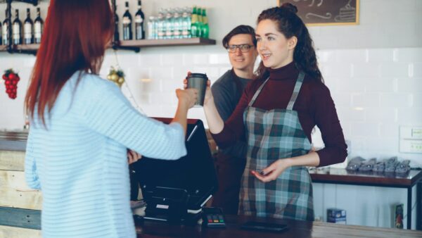 Barista handing a customer a warm welcome and a coffee