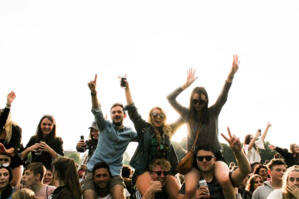 People celebrating with arms raised at an outdoor music festival