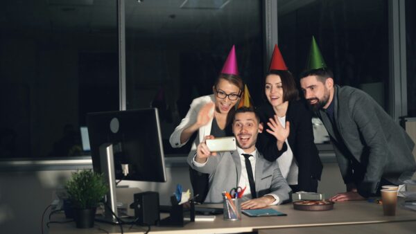 Colleagues in party hats laughing and taking a selfie