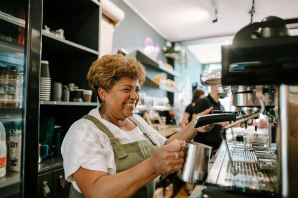 Smiling cafe owner making coffee behind the counter