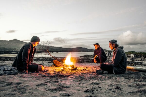 Three men in front of a beach bonfire
